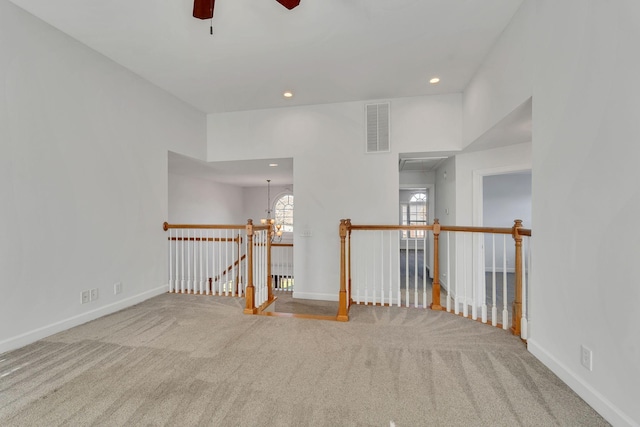 spare room with ceiling fan with notable chandelier, carpet, visible vents, and baseboards