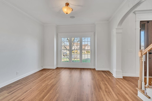 empty room with arched walkways, light wood-style flooring, baseboards, and ornamental molding