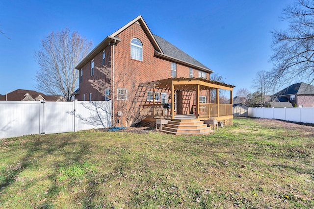 rear view of house featuring a deck, a pergola, a fenced backyard, a yard, and brick siding