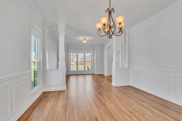 unfurnished dining area featuring a notable chandelier, light wood finished floors, and ornamental molding