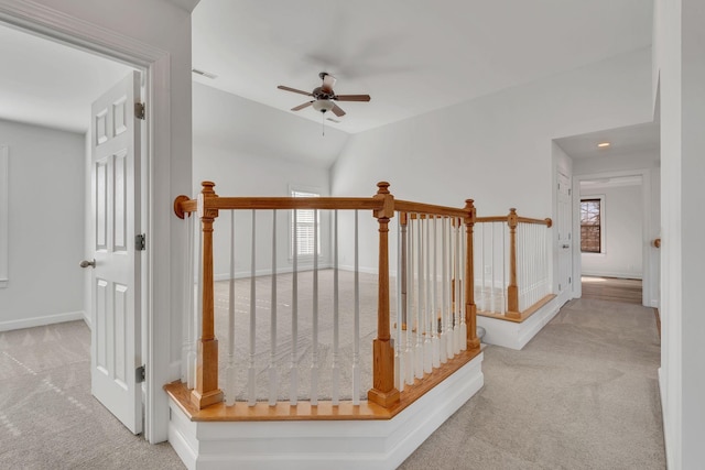 hall with vaulted ceiling, an upstairs landing, baseboards, and carpet floors