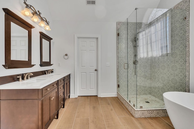 full bath with a shower stall, a freestanding bath, and a sink