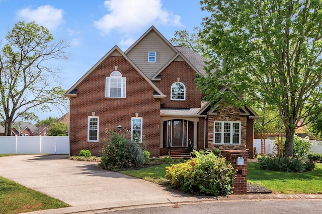 traditional-style home with concrete driveway, brick siding, and fence