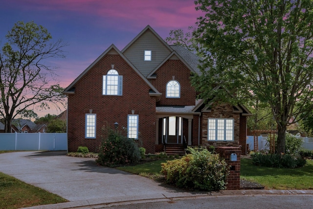 traditional-style home with brick siding, concrete driveway, and fence