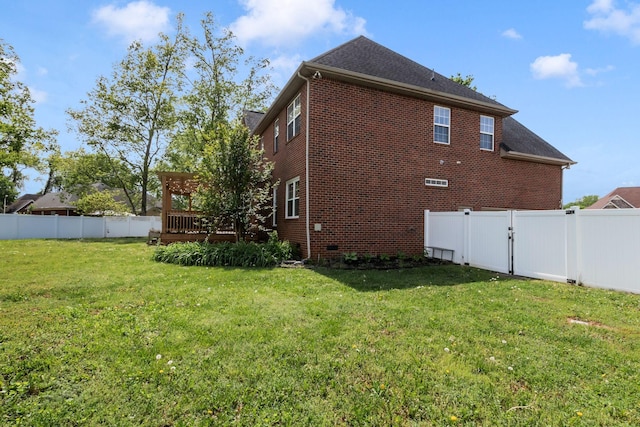 view of side of home featuring a gate, a fenced backyard, a yard, a wooden deck, and brick siding
