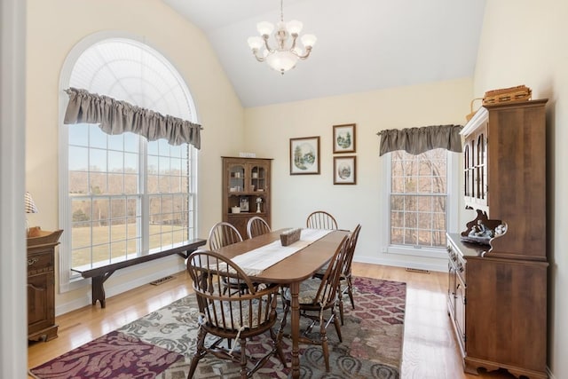 dining area featuring vaulted ceiling, visible vents, light wood-type flooring, and a chandelier