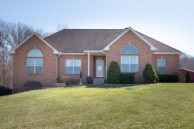 single story home featuring brick siding, a front yard, and a shingled roof