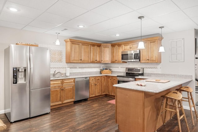 kitchen featuring decorative backsplash, appliances with stainless steel finishes, a peninsula, dark wood-style floors, and a sink