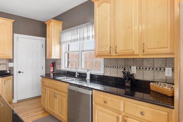 kitchen featuring dark stone counters, a sink, light brown cabinetry, dishwasher, and tasteful backsplash