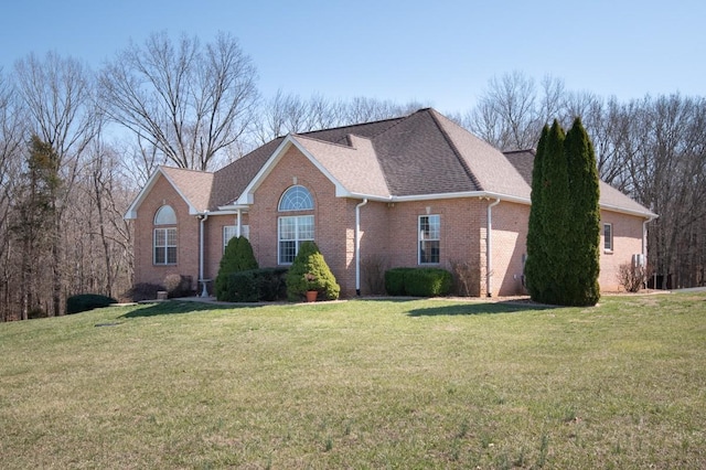 view of front of home with brick siding, a front lawn, and a shingled roof