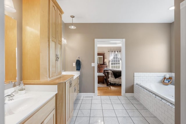 bathroom with vanity, baseboards, tiled tub, tile patterned flooring, and connected bathroom