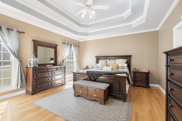 bedroom featuring ceiling fan, light wood-type flooring, a raised ceiling, and baseboards