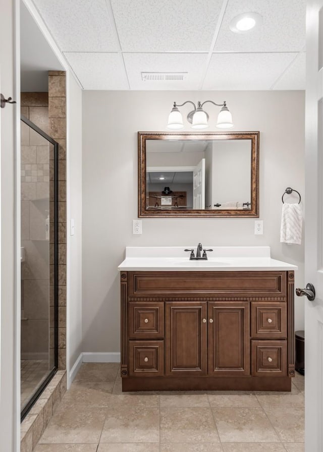 bathroom featuring vanity, baseboards, visible vents, a stall shower, and a drop ceiling