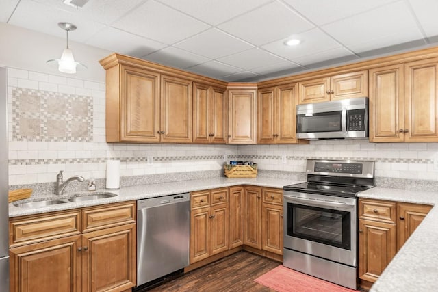 kitchen with a sink, dark wood finished floors, appliances with stainless steel finishes, decorative backsplash, and hanging light fixtures