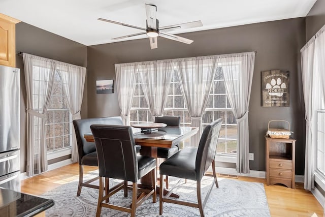 dining space with baseboards, light wood-style floors, visible vents, and ceiling fan