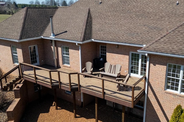 rear view of house with stairway, brick siding, roof with shingles, and a deck