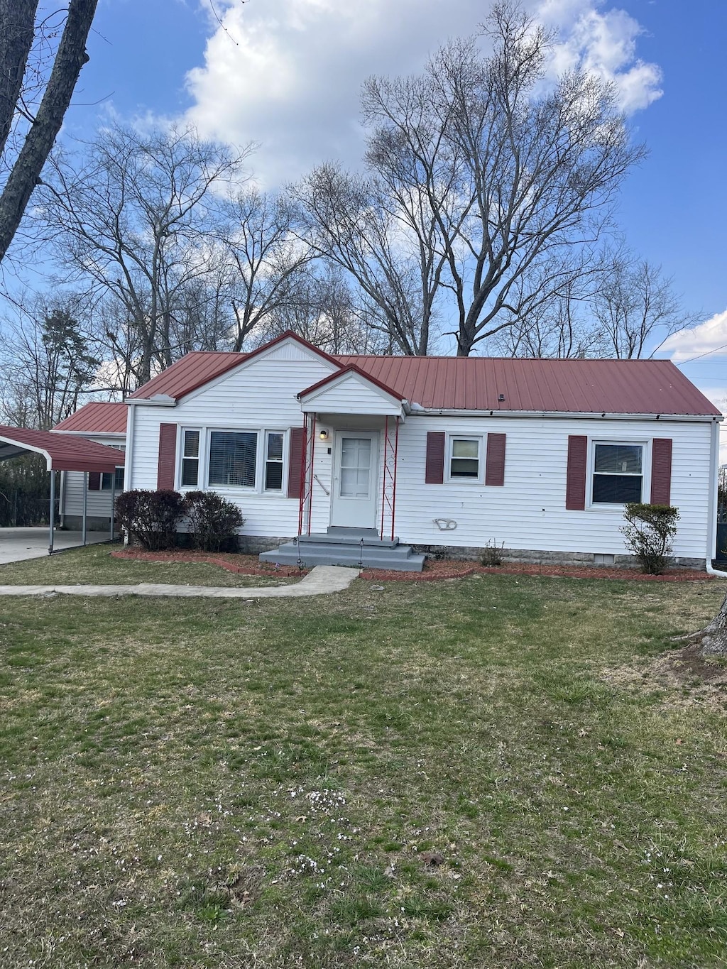 view of front of house featuring crawl space, metal roof, a carport, and a front lawn