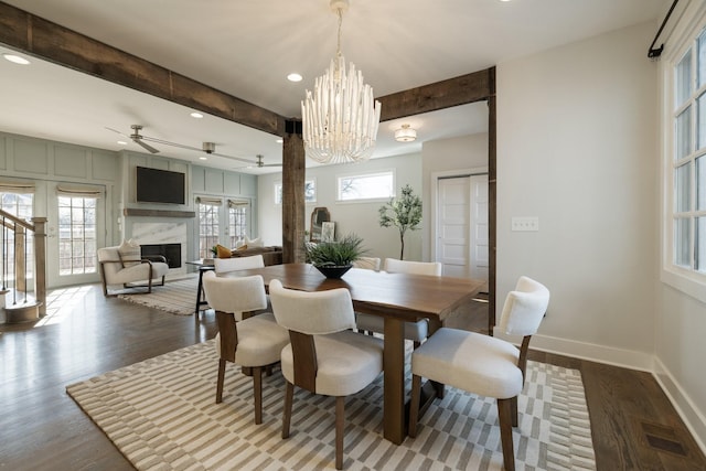 dining room with visible vents, beam ceiling, wood finished floors, a fireplace, and baseboards