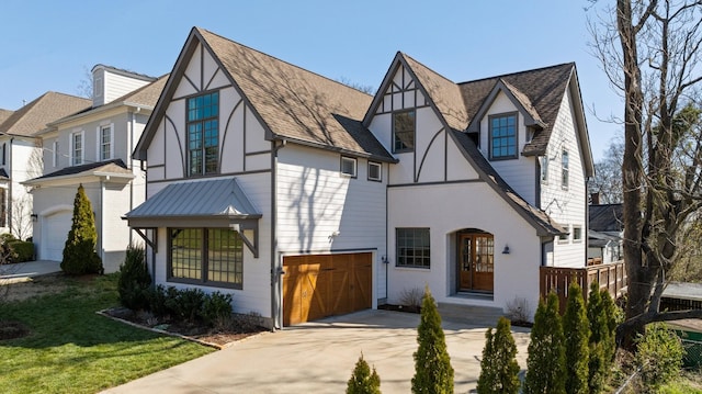 tudor-style house featuring brick siding, a garage, driveway, and stucco siding