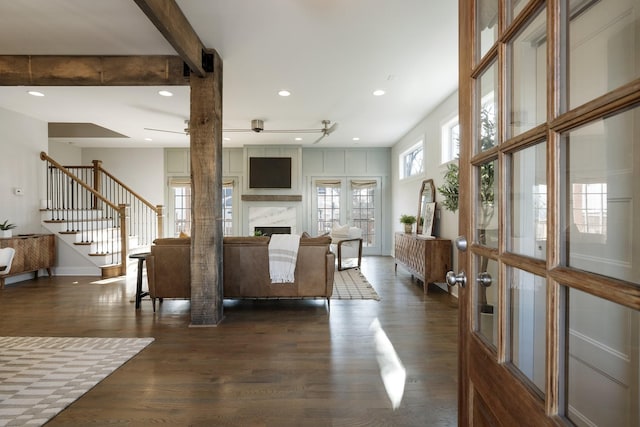 living room featuring stairway, dark wood-type flooring, a ceiling fan, and a premium fireplace