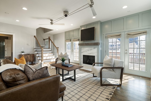 living area with stairway, plenty of natural light, light wood-style flooring, and a fireplace