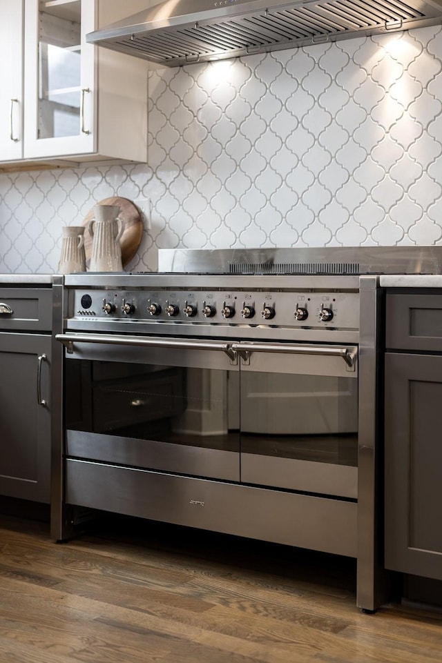 kitchen with glass insert cabinets, double oven range, light countertops, decorative backsplash, and dark wood-style flooring