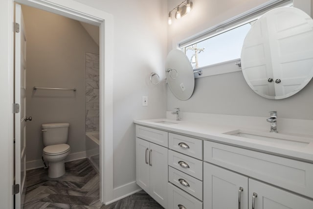 bathroom with double vanity, toilet, baseboards, and a sink