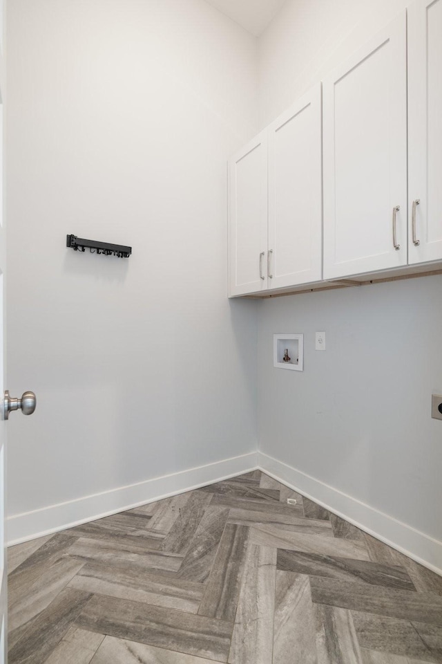 clothes washing area with cabinet space, hookup for an electric dryer, hookup for a washing machine, and baseboards