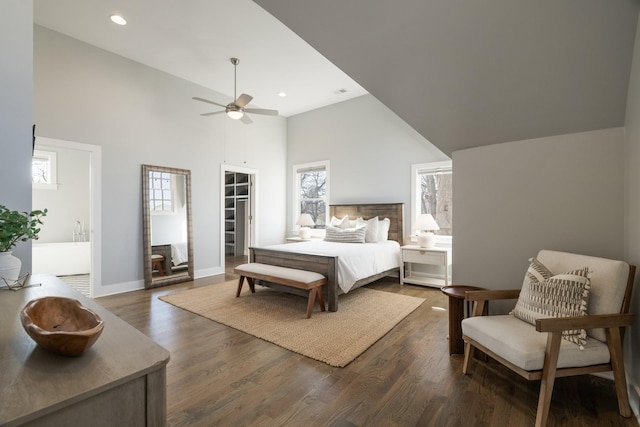 bedroom featuring multiple windows, dark wood-style floors, and a towering ceiling