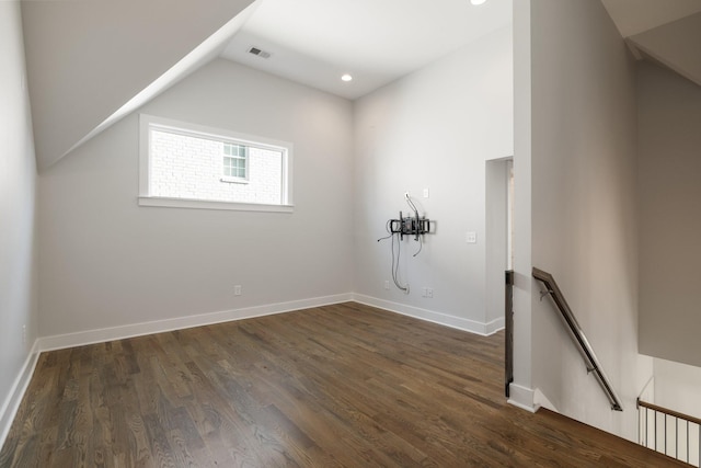 empty room featuring visible vents, lofted ceiling, baseboards, and dark wood finished floors