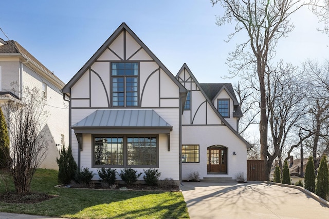 english style home with a standing seam roof, a front yard, and metal roof