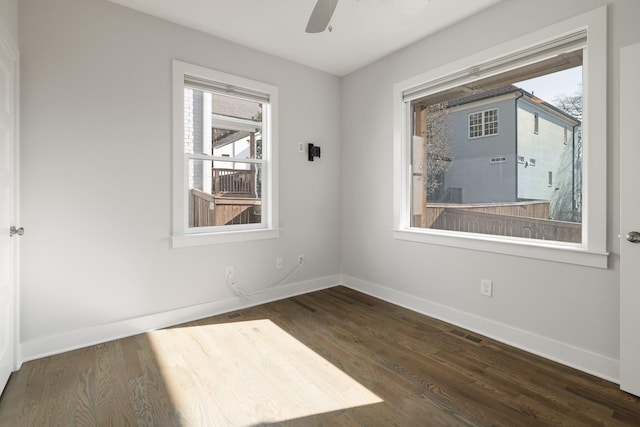 spare room with dark wood finished floors, visible vents, ceiling fan, and baseboards