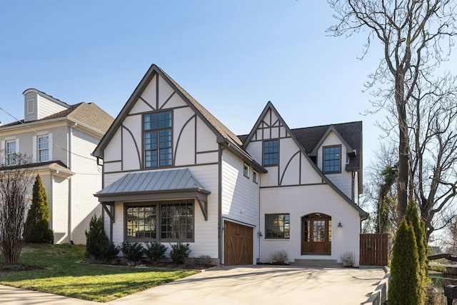 english style home featuring a standing seam roof, a front lawn, a garage, and driveway