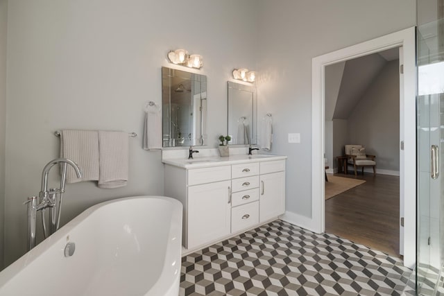 bathroom featuring a shower stall, baseboards, a freestanding bath, double vanity, and a sink