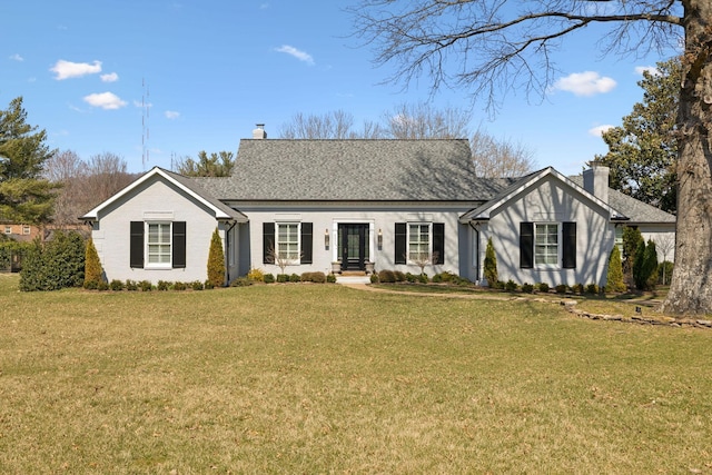 view of front facade with a front lawn, roof with shingles, and a chimney