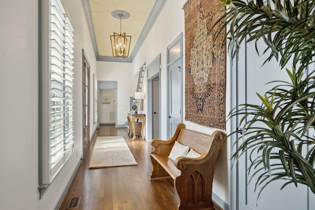 hallway featuring crown molding, a notable chandelier, wood finished floors, and visible vents