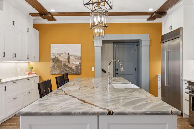 kitchen with a large island, beam ceiling, white cabinets, and stainless steel appliances