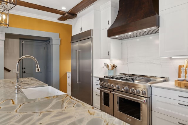 kitchen with a sink, tasteful backsplash, white cabinets, custom exhaust hood, and high end appliances