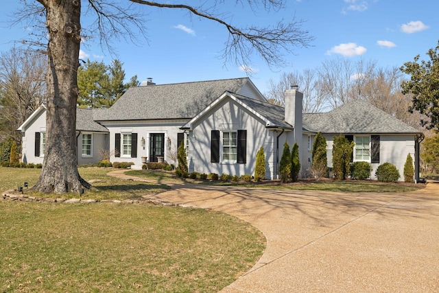 view of front of house featuring driveway, a chimney, and a front yard