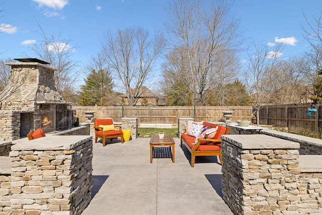 view of patio featuring an outdoor living space with a fireplace and a fenced backyard