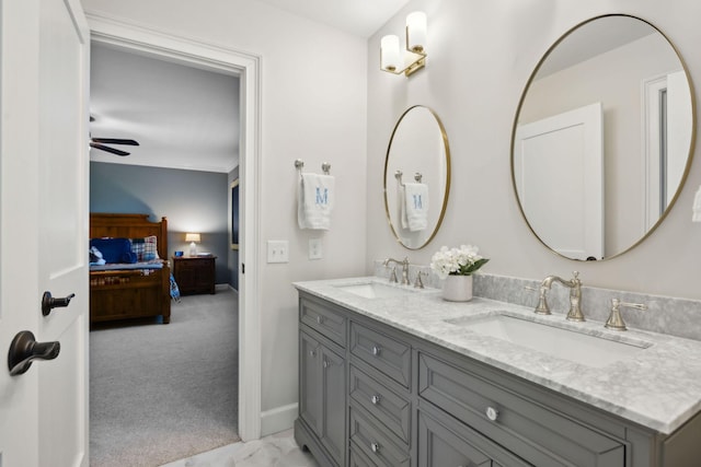 bathroom with a sink, connected bathroom, baseboards, and double vanity