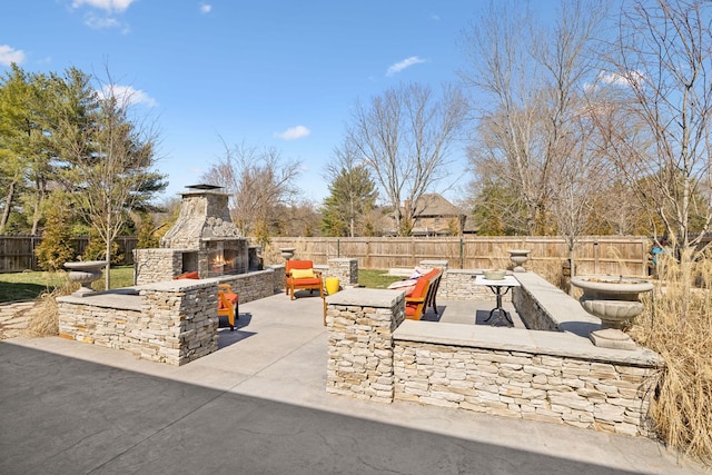 view of patio / terrace featuring an outdoor stone fireplace and a fenced backyard