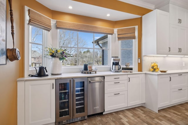 kitchen with wine cooler, light countertops, and white cabinetry