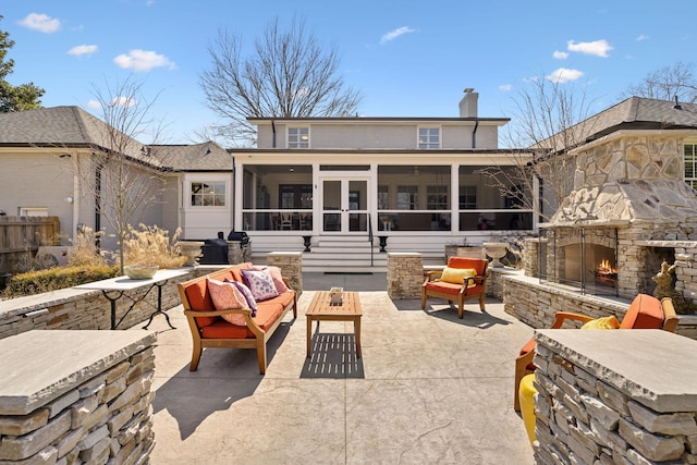 rear view of house with fence, an outdoor living space with a fireplace, a sunroom, a chimney, and a patio area