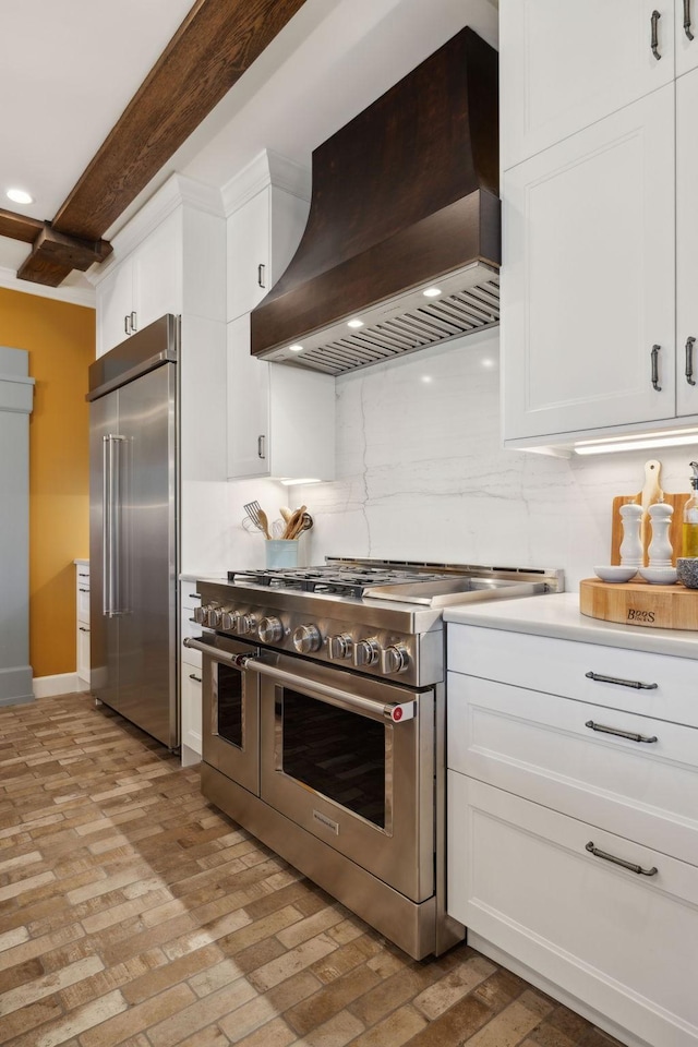 kitchen with white cabinetry, custom exhaust hood, premium appliances, and backsplash