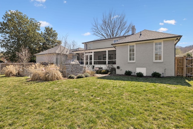 back of house with a yard, fence, brick siding, and a sunroom