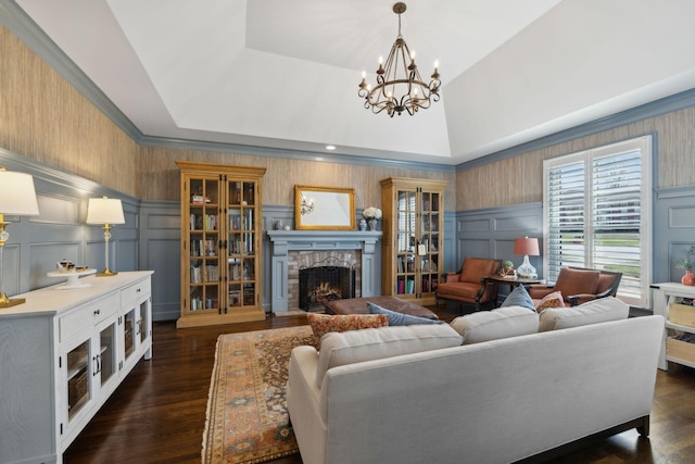 living room featuring a notable chandelier, a stone fireplace, and a decorative wall