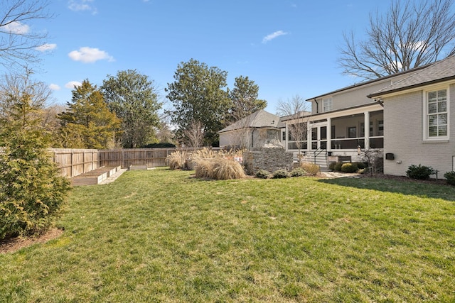 view of yard featuring a garden, a fenced backyard, and a sunroom