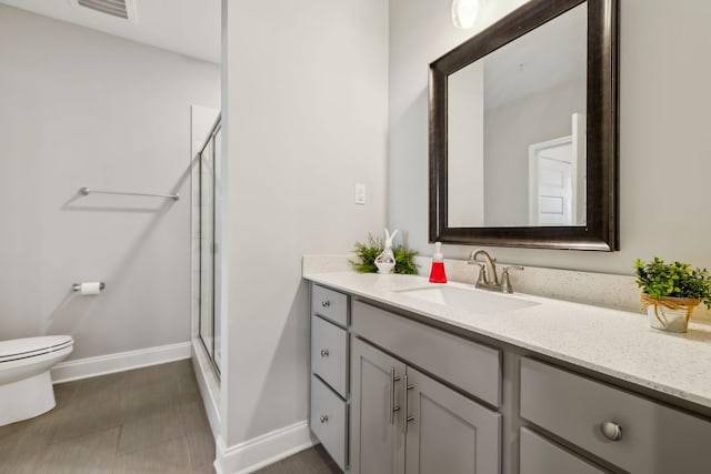 bathroom featuring vanity, baseboards, visible vents, a stall shower, and toilet