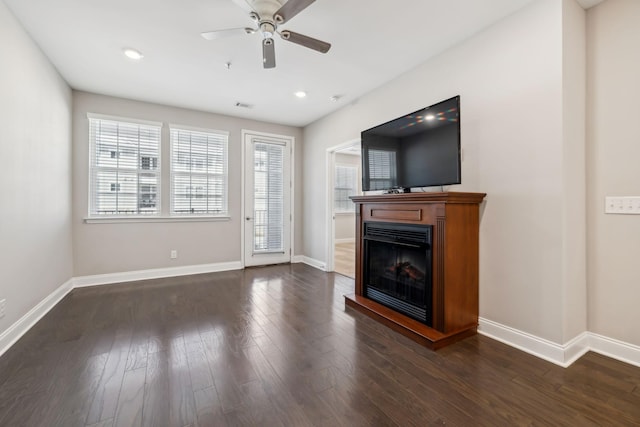 unfurnished living room featuring dark wood finished floors, a fireplace, baseboards, and ceiling fan